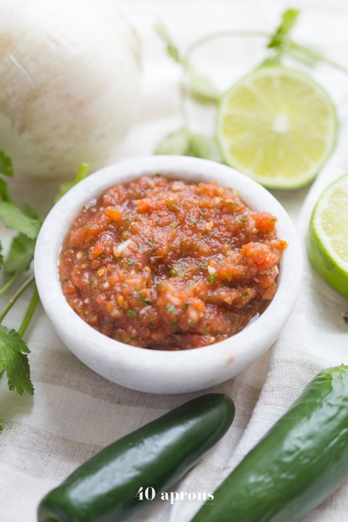 This is the best restaurant style salsa recipe, and I've been making it blissfully for almost a decade! What makes this the best restaurant-style salsa recipe? Spoiler alert: it comes from one of my favorite Mexican restaurants (but I'll never say which)! It blends fresh garlic, cilantro, chiles, onions, and tomatoes with canned tomatoes for the perfect blend of fresh and traditional restaurant style salsa. So good!