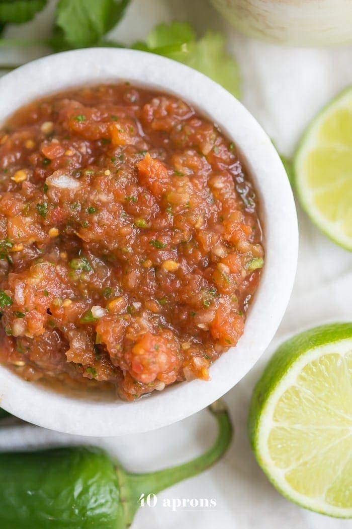 This is the best restaurant style salsa recipe, and I've been making it blissfully for almost a decade! What makes this the best restaurant style salsa recipe? Spoiler alert: it comes from one of my favorite Mexican restaurants (but I'll never say which)! It blends fresh garlic, cilantro, chiles, onions, and tomatoes with canned tomatoes for the perfect blend of fresh and traditional restaurant style salsa. So good!