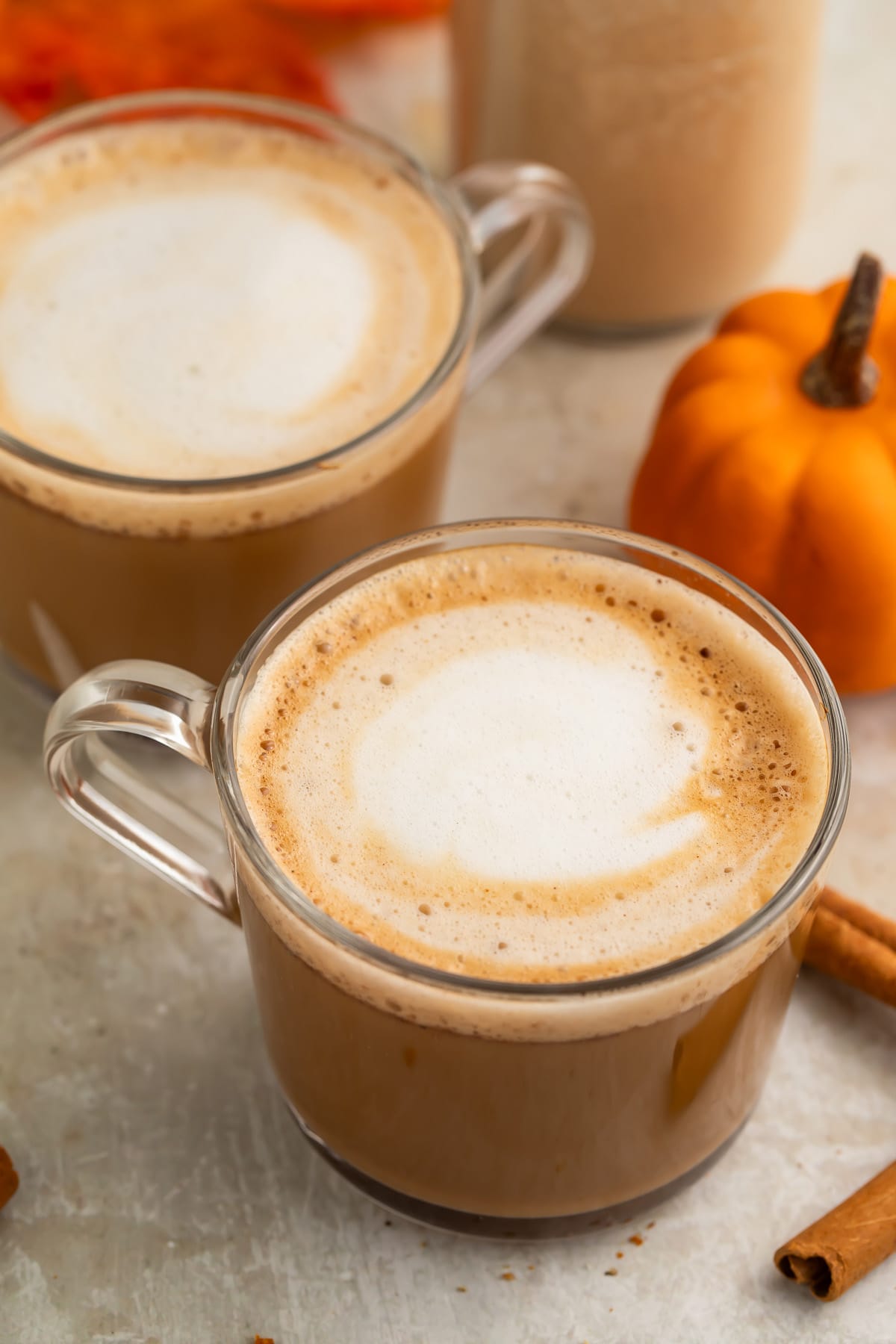 Two clear glass coffee mugs holding a pumpkin spice latte with rich pumpkin spice creamer.