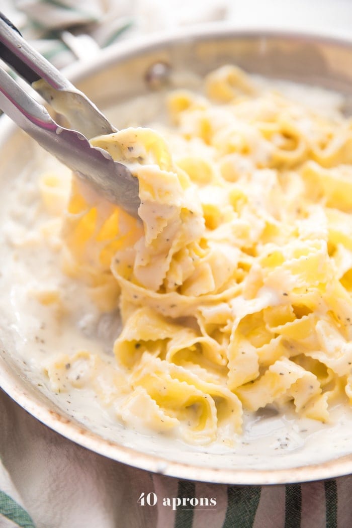 Cottage cheese alfredo in a saucepan with fettuccine and tongs