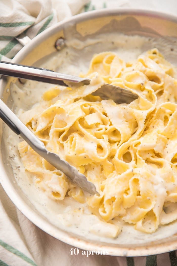 Cottage cheese alfredo in a saucepan with fettuccine and tongs