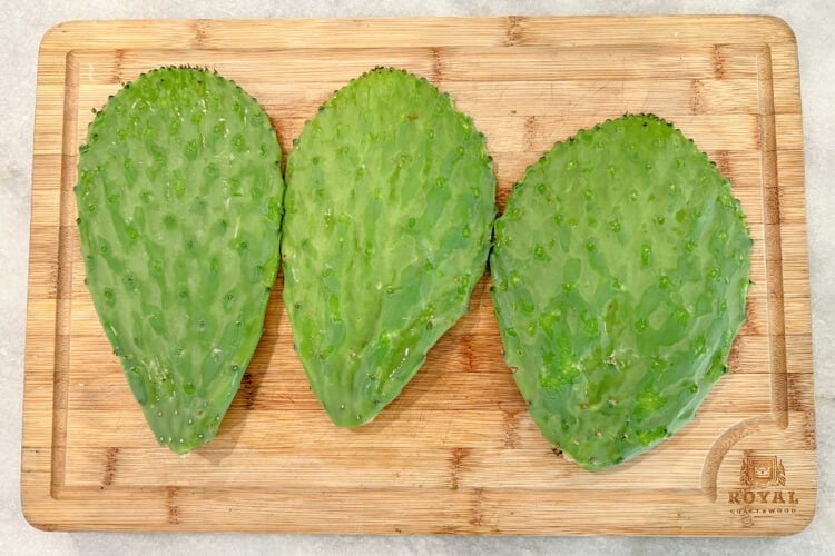 Three nopales paddles on a cutting board, knobs and spines removed.