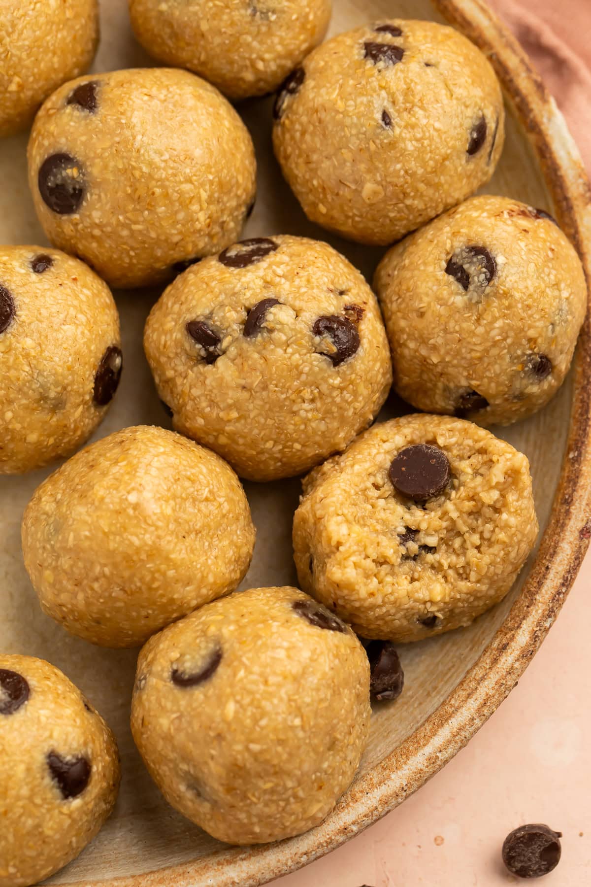 Close up of a plate of chocolate chip cookie dough energy balls with one missing a bite.