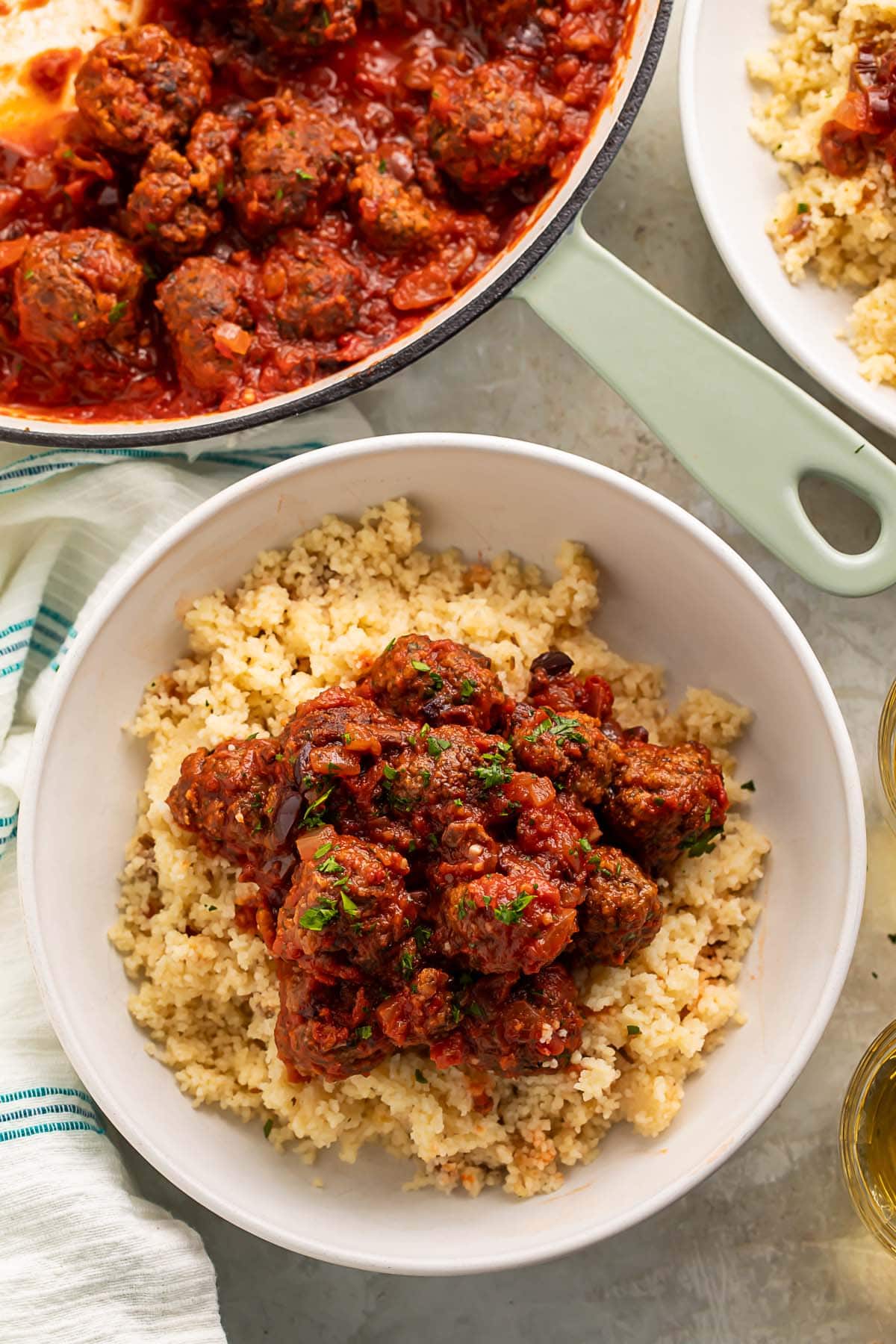 Moroccan meatballs served over a bed of fluffy couscous in a large white bowl.