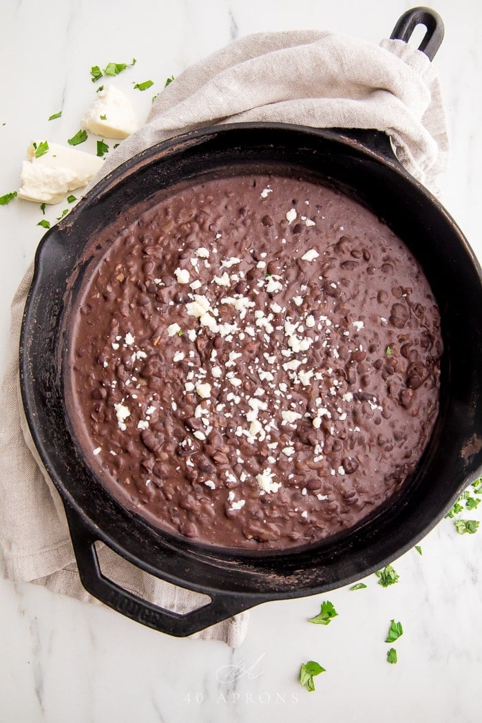 Skillet of refried black beans with queso fresco on top