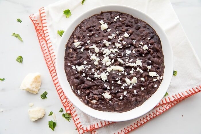 Bowl of refried black beans on a napkin with queso fresco