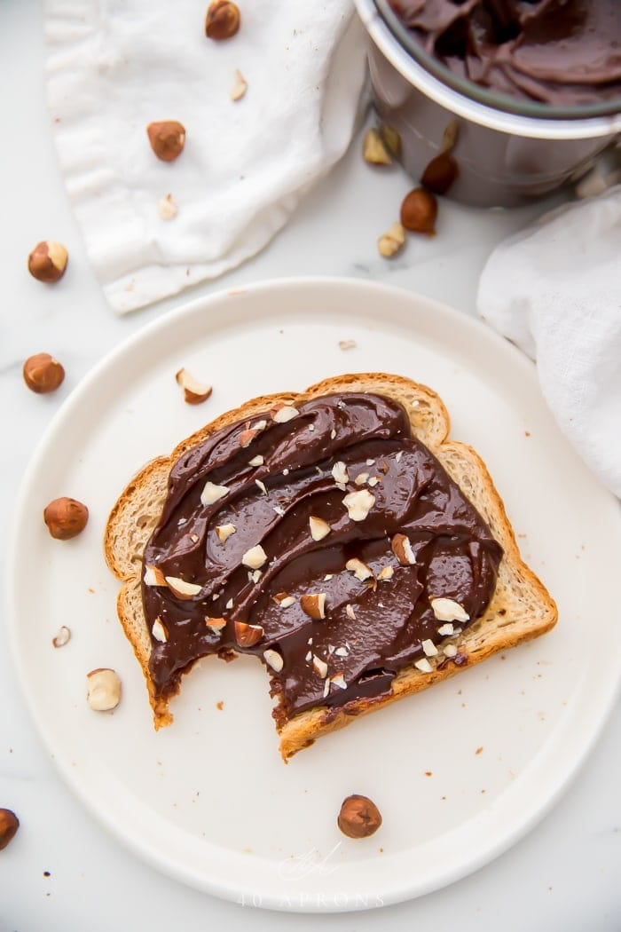 Slice of toast with Nutella spread on it and a bite taken out