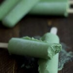Green tea coconut popsicles, with one bite missing from a popsicle stacked on another popsicle.