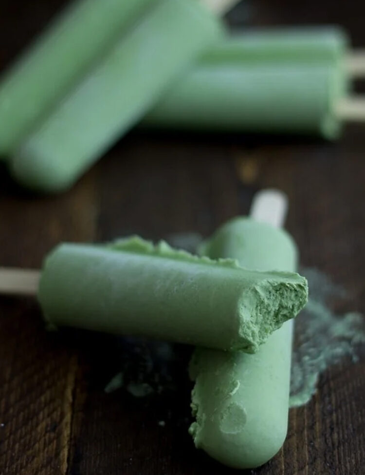 Green tea coconut popsicles, with one bite missing from a popsicle stacked on another popsicle.