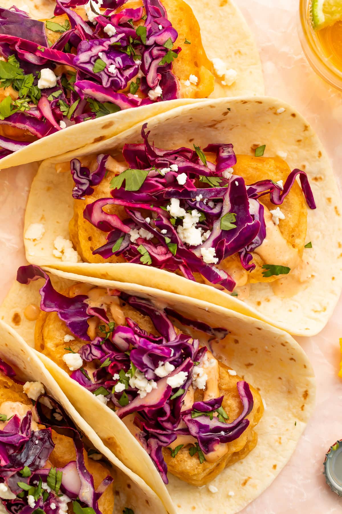 Overhead view of three beer battered tofu tacos topped with red cabbage slaw and crumbled cheese