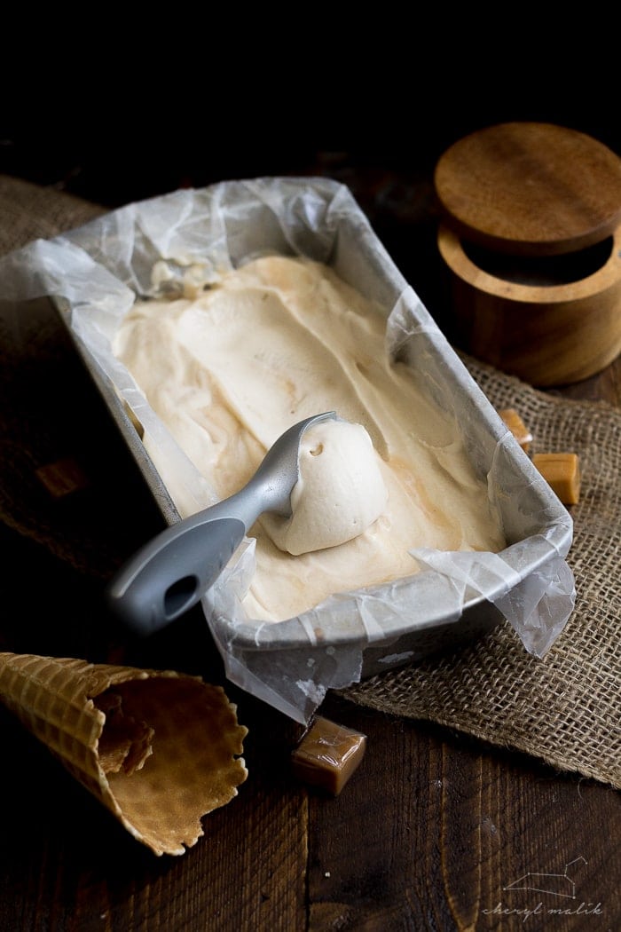 Salted caramel vegan ice cream in a loaf pan with an ice cream scoop