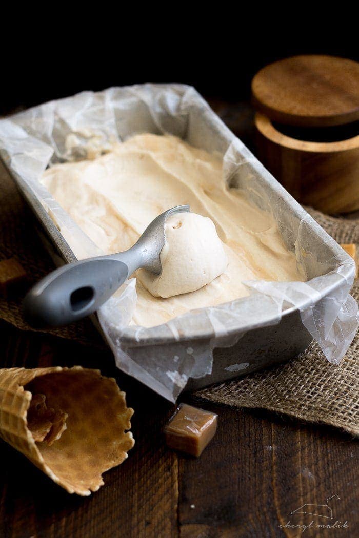 Salted caramel vegan ice cream in a loaf pan with an ice cream scoop