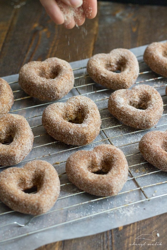 Baked apple cider donuts rolled in cinnamon sugar and topped with pomegranate glaze. Perfect for fall and so moist!