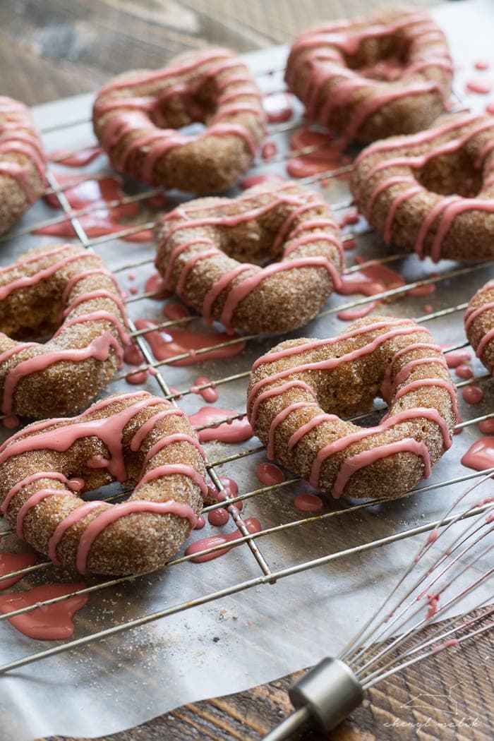 Baked apple cider donuts rolled in cinnamon sugar and topped with pomegranate glaze. Perfect for fall and so moist!