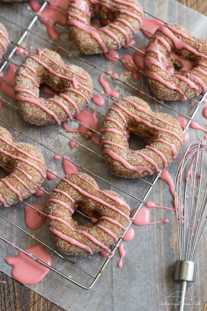 Baked apple cider donuts rolled in cinnamon sugar and topped with pomegranate glaze. Perfect for fall and so moist!