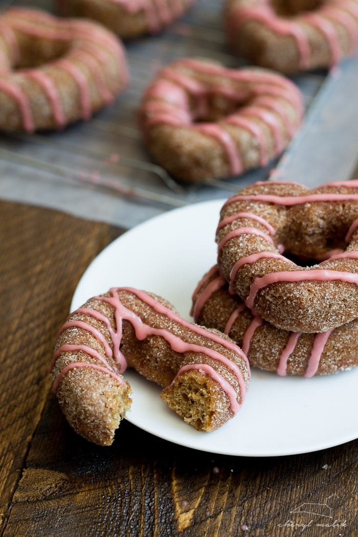 Baked apple cider donuts rolled in cinnamon sugar and topped with pomegranate glaze. Perfect for fall and so moist!