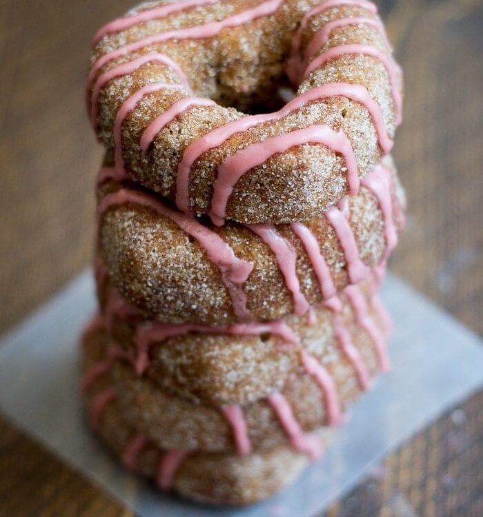 Baked apple cider donuts rolled in cinnamon sugar and topped with pomegranate glaze. Perfect for fall and so moist!