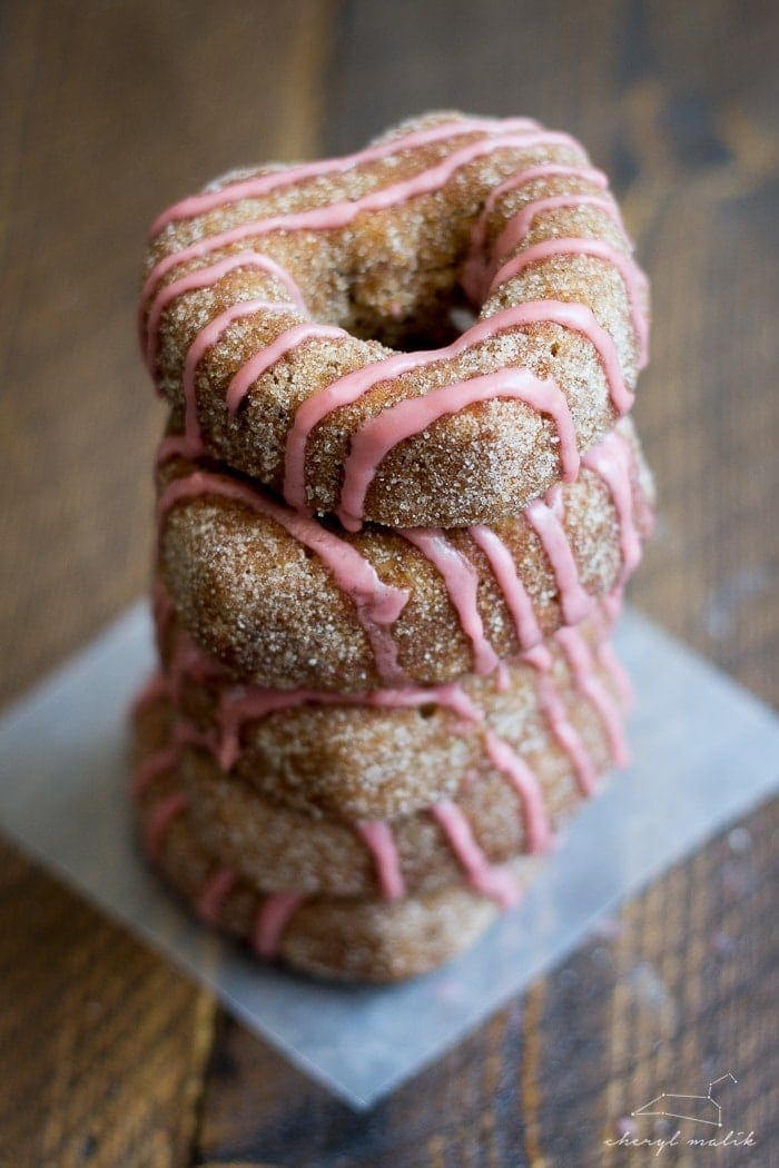 Baked apple cider donuts rolled in cinnamon sugar and topped with pomegranate glaze. Perfect for fall and so moist!