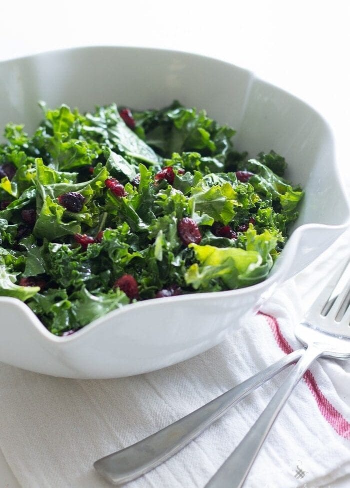 A bright and light raw kale salad tossed in a lemony honey vinaigrette and dotted with sweet, tart dried cranberries. The perfect side dish for a heavy holiday feast!