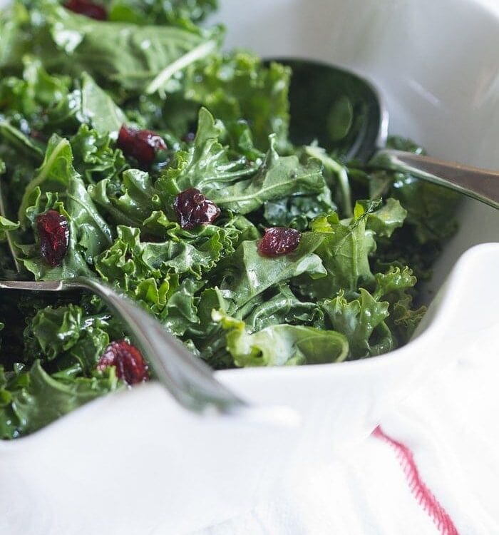 A bright and light raw kale salad tossed in a lemony honey vinaigrette and dotted with sweet, tart dried cranberries. The perfect side dish for a heavy holiday feast!