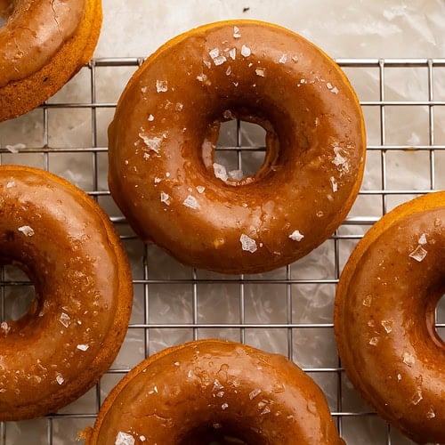 Vegan pumpkin donuts with salted caramel glaze on wire cooling rack with sea salt flakes
