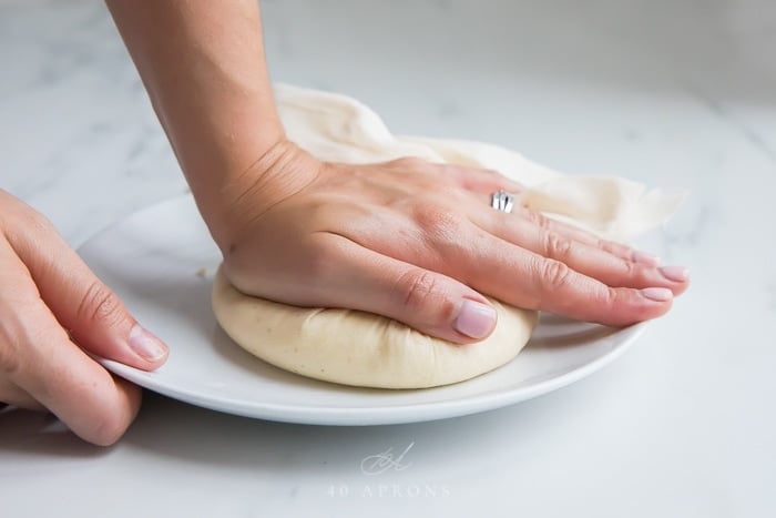 Flattening a ball of curds to make paneer