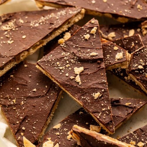 Broken pieces of saltine toffee in a pile on a piece of parchment paper.