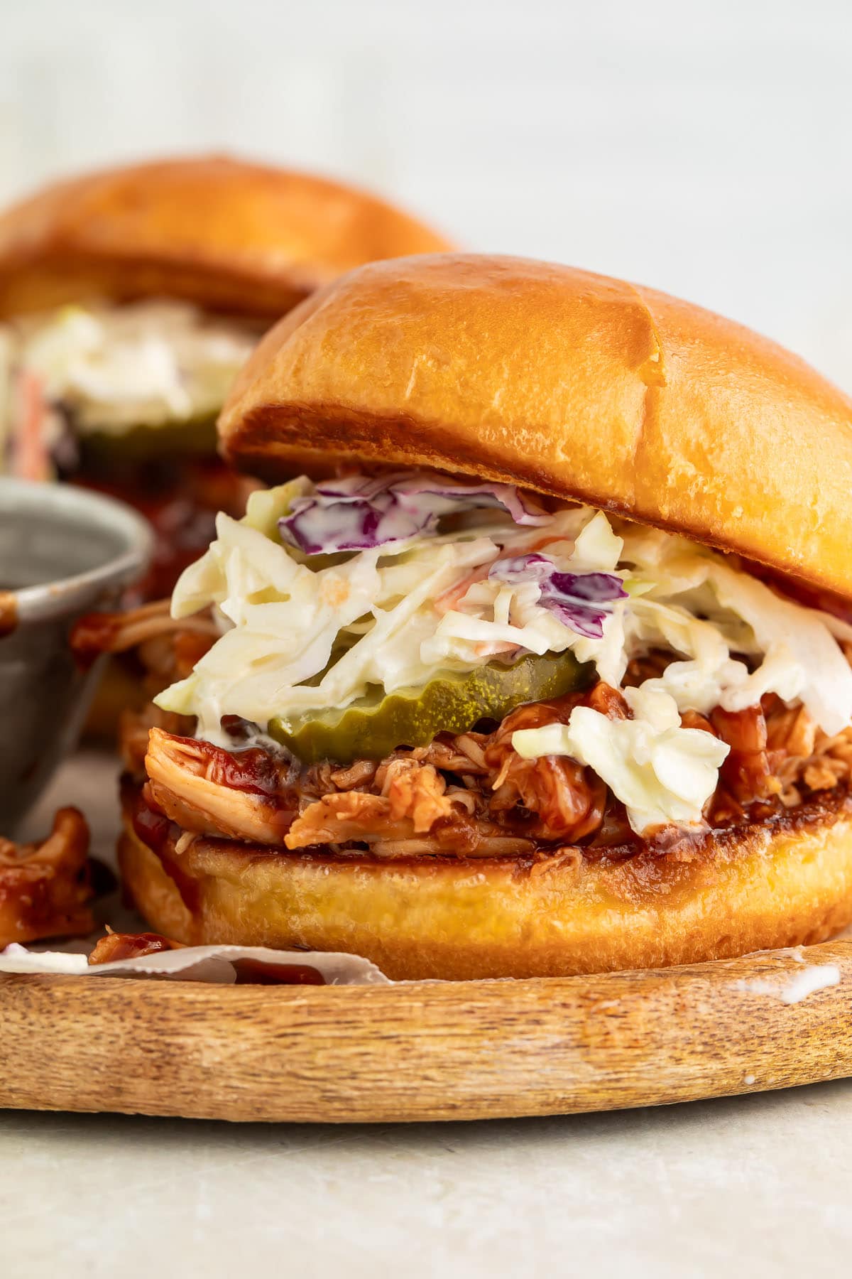 Crockpot-cooked pulled BBQ chicken on a sandwich bun with pickle chips and coleslaw.