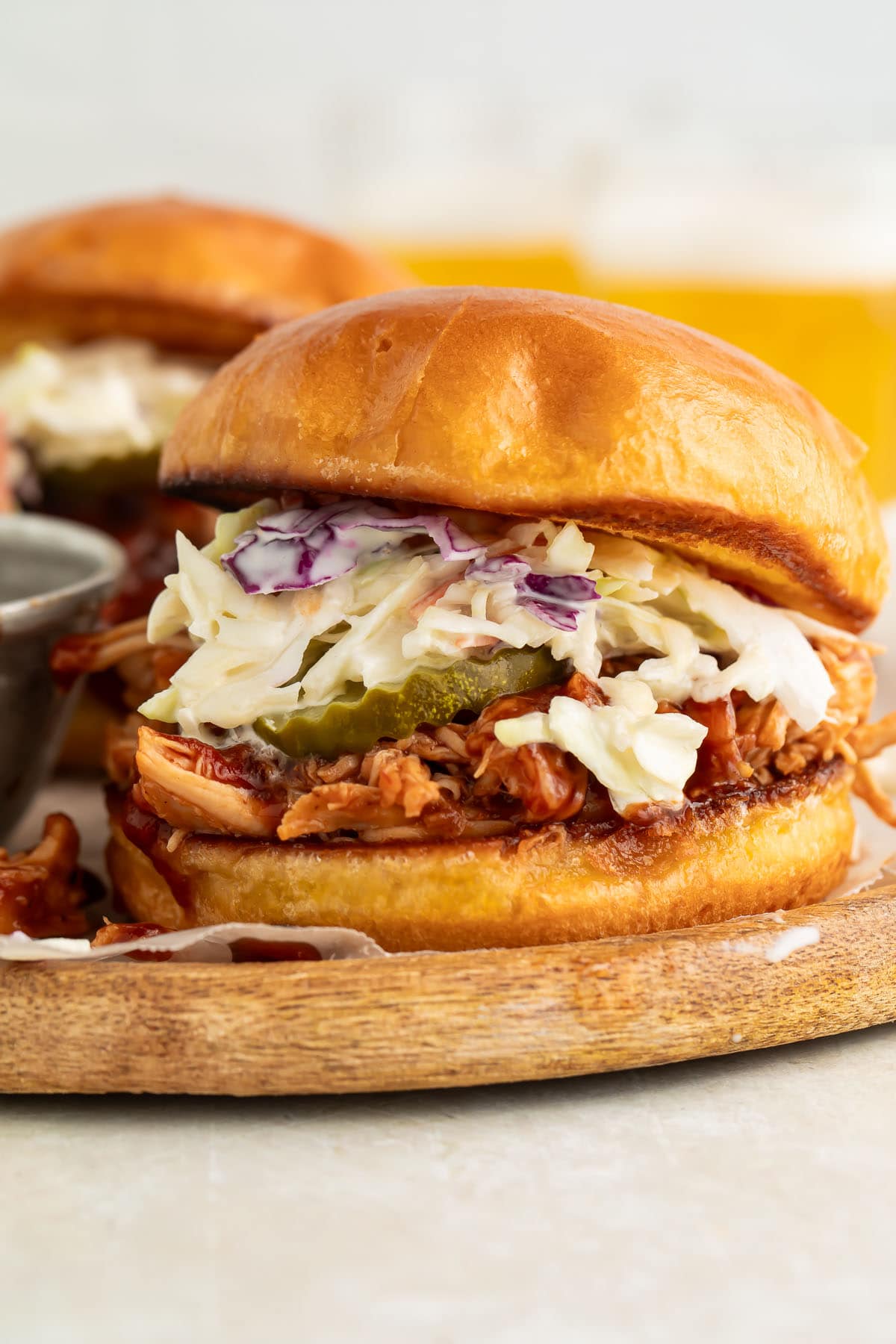 Crockpot-cooked pulled BBQ chicken on a sandwich bun with pickle chips and coleslaw.
