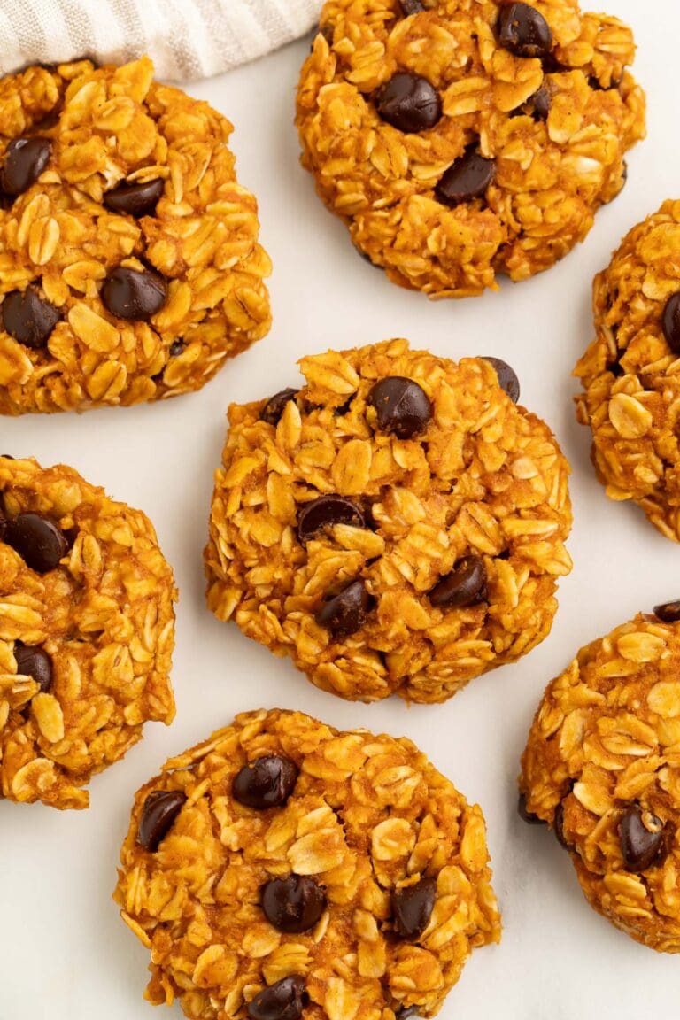 No-bake pumpkin oatmeal cookies dotted with chocolate chips arranged on a sheet of parchment paper.