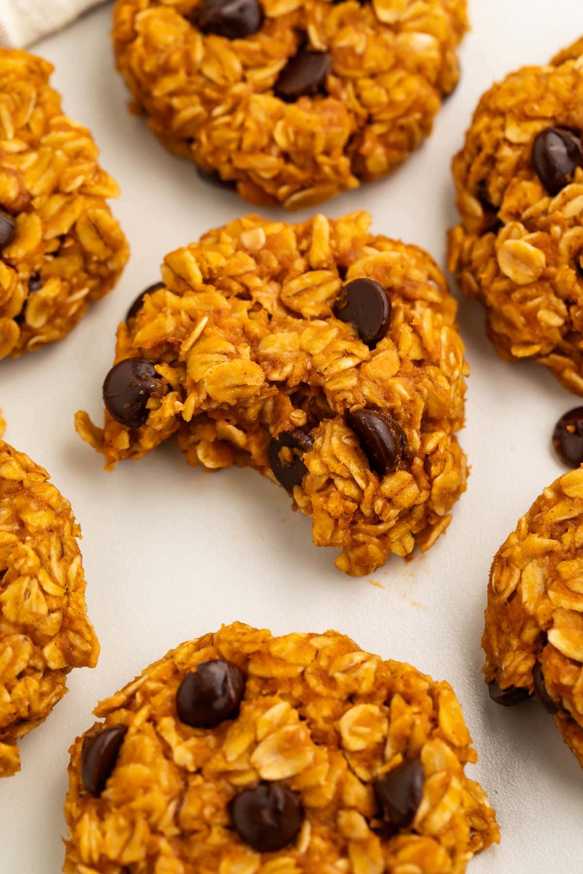 No-bake pumpkin oatmeal cookies dotted with chocolate chips arranged on a sheet of parchment paper.