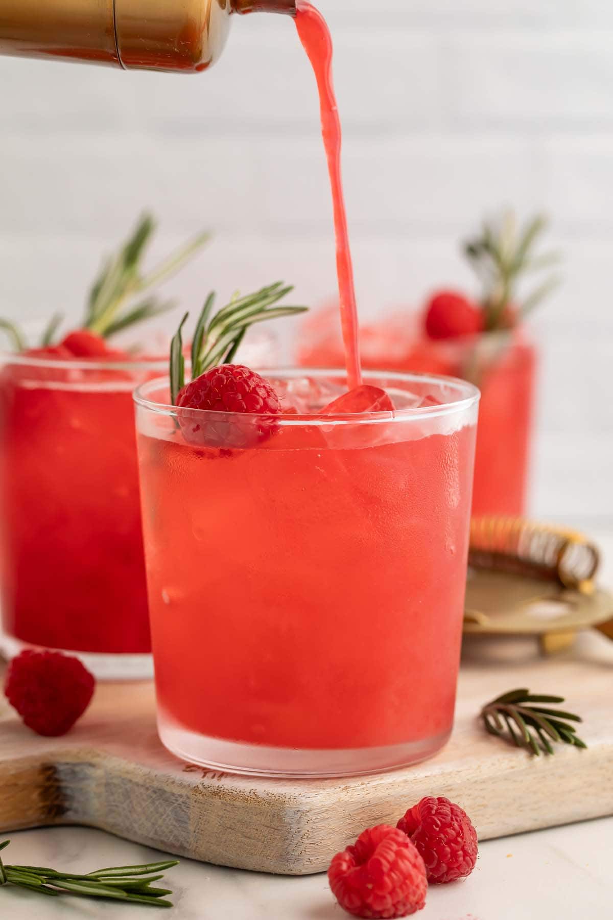 A raspberry cocktail being poured from a cocktail shaker into a glass.