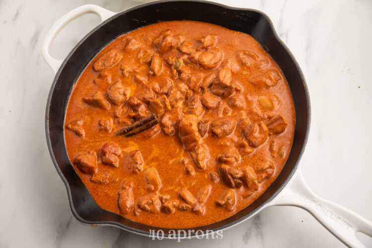 Indian butter chicken in a large wok on a neutral background.