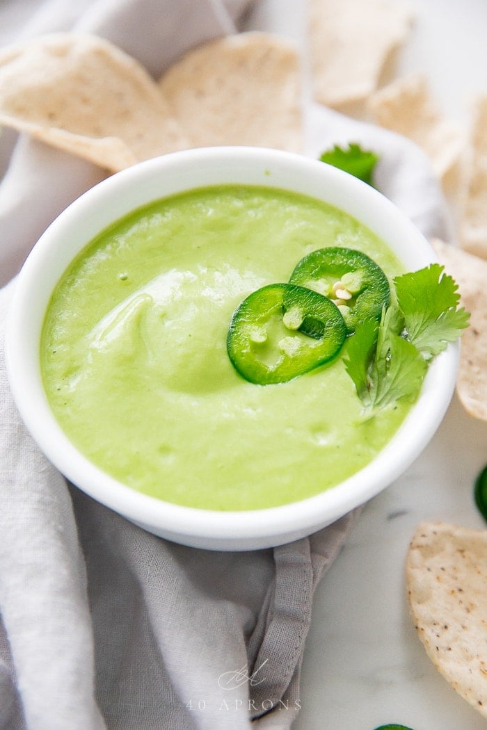 Salsa de abacate numa tigela branca num ângulo, rodeada de batatas fritas