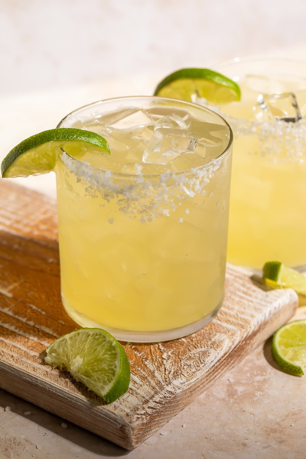 Close up of a honey margarita with a salt rim on a wooden board.