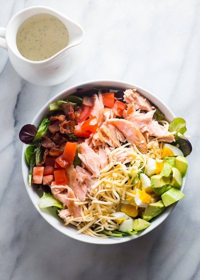 An absolute explosion of flavor, this smoked salmon cobb salad is layered with crisp bacon, creamy smoked gouda, cubed avocado, and tender boiled eggs.