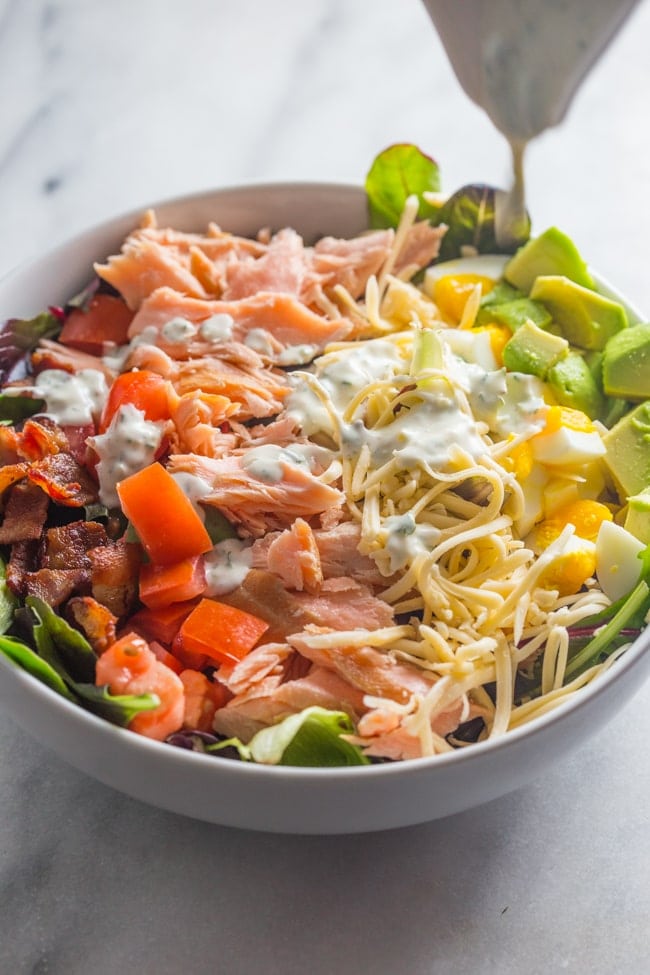 An absolute explosion of flavor, this smoked salmon cobb salad is layered with crisp bacon, creamy smoked gouda, cubed avocado, and tender boiled eggs.