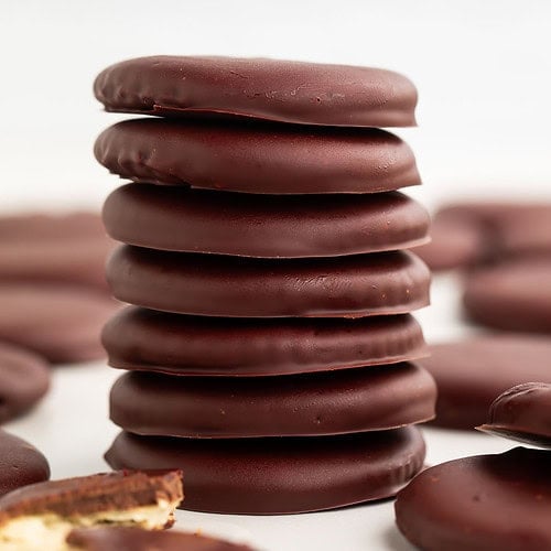 A short stack of vegan thin mints on a table surrounded by other thin mint cookies.