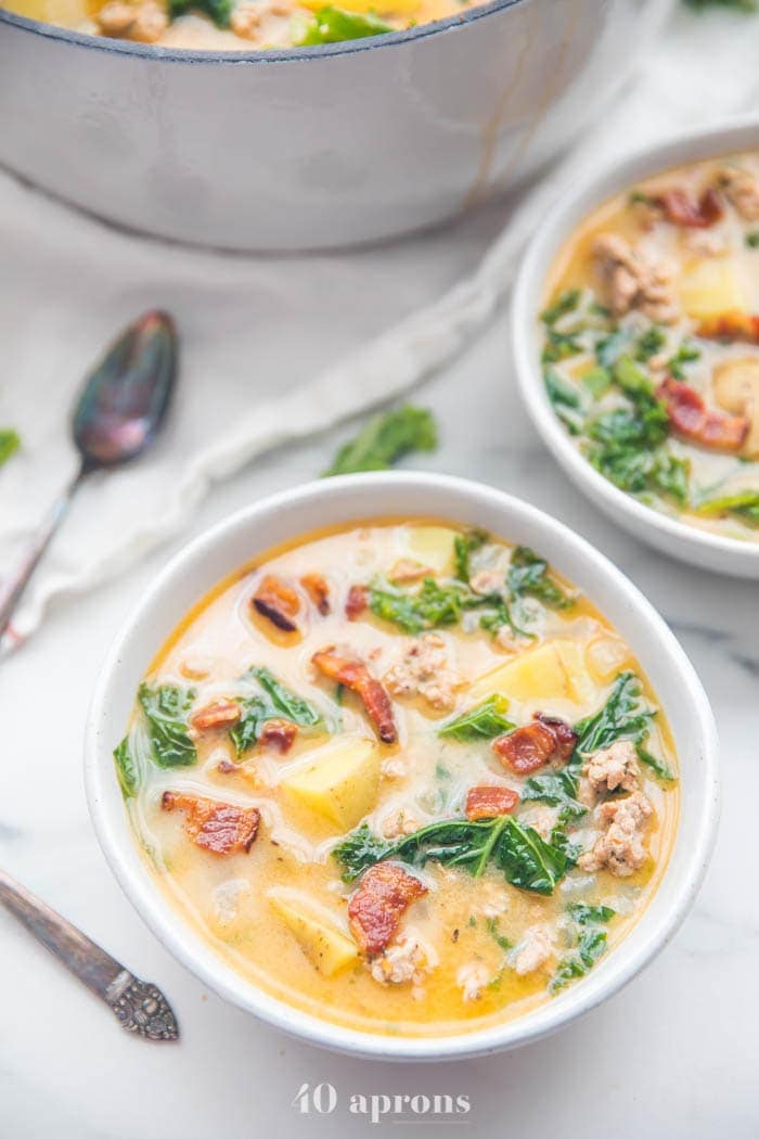 Two bowls of Whole30 healthy zuppa toscana recipe with a pot in the background