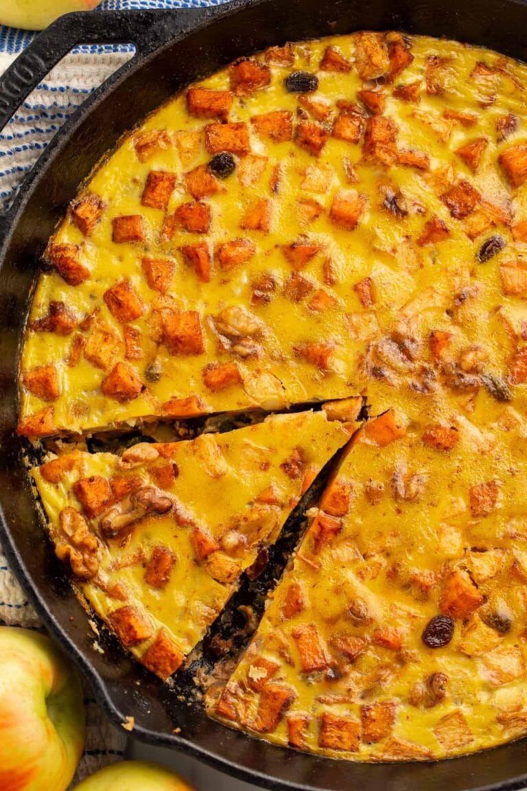 A large cast iron skillet holding a paleo breakfast bake. A wedge of the bake has been sliced already.