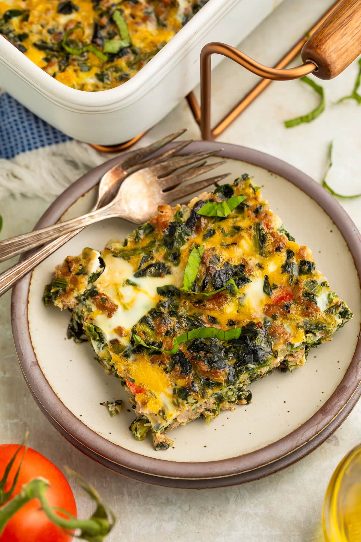 Slice of Whole30 breakfast bake with sausage, eggs, spinach, and bell peppers on a cream plate with a fork