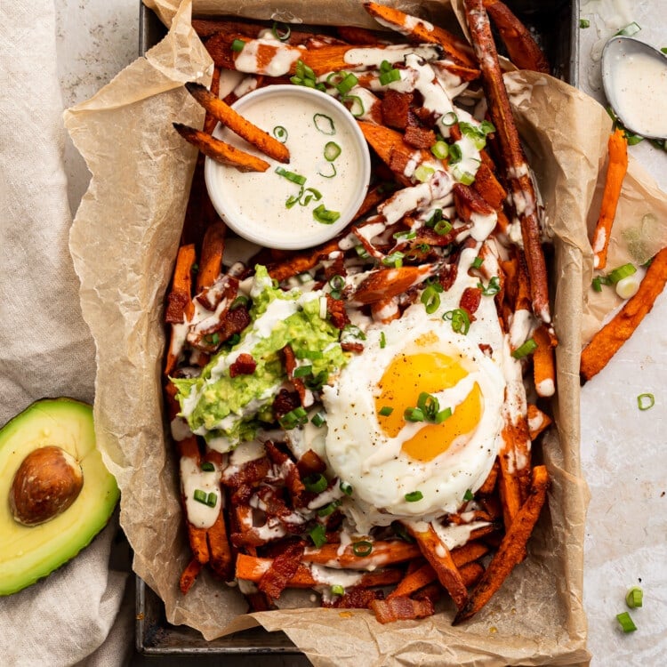 Whole30 Loaded Sweet Potato Fries in a parchment paper lined dish, shot from overhead