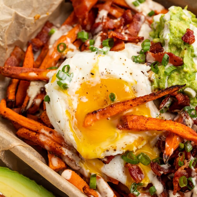 Close-up overhead view of Whole30 Loaded Sweet Potato Fries dipped into a fried egg