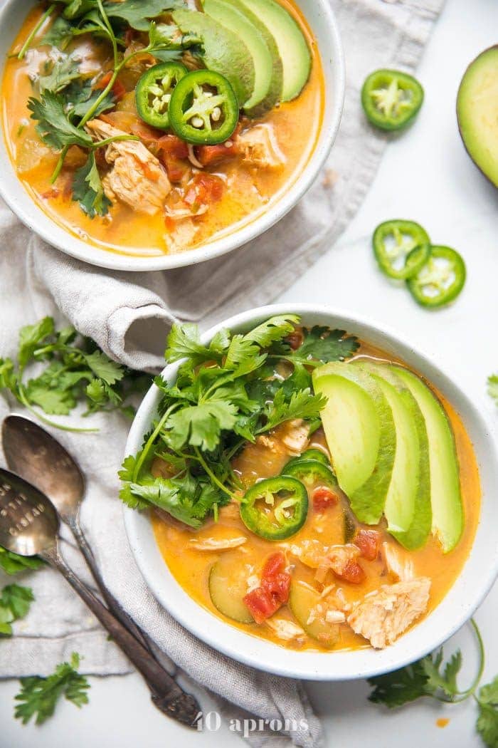 Whole30 Instant Pot chicken tortilla less soup in two bowls garnished with avocado, cilantro, jalapenos