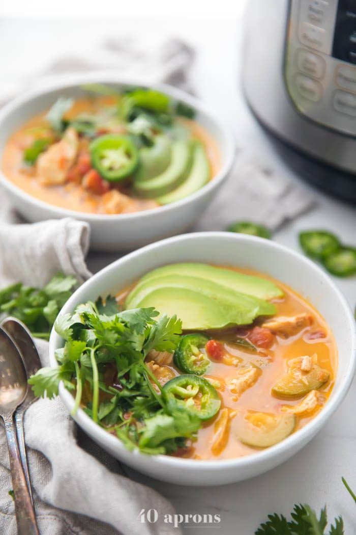 Whole30 Instant Pot chicken tortilla less soup in two bowls garnished with avocado, cilantro, jalapenos