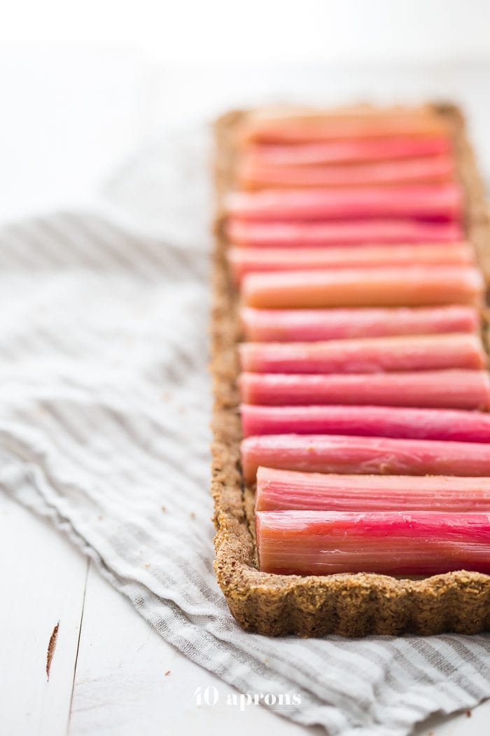 This paleo rhubarb tart is layered with a buttery shortbread crust, rich almond frangiapane filling, and finished with a perfectly sweet, tart rhubarb topping. This paleo rhubarb dessert is absolutely stunning and positively delicious, making it perfect for summer entertaining. This paleo rhubarb tart is a must-try!