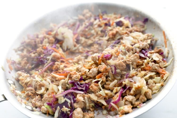 Egg roll in a bowl mixture in a large silver skillet.