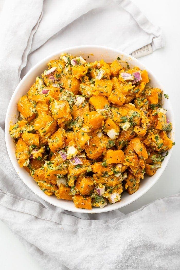 Sweet potato salad in a white bowl on a marble countertop