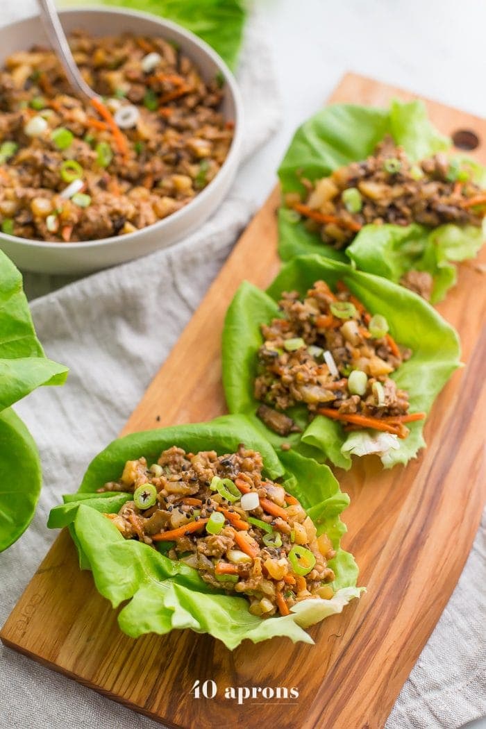 Healthy PF Changs lettuce wraps recipe on a board with a bowl of filling to the side