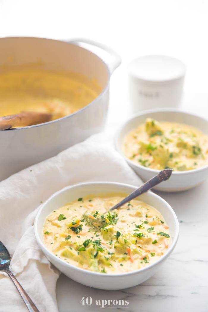 Cheesy vegan broccoli soup in two bowls with soup pot in background